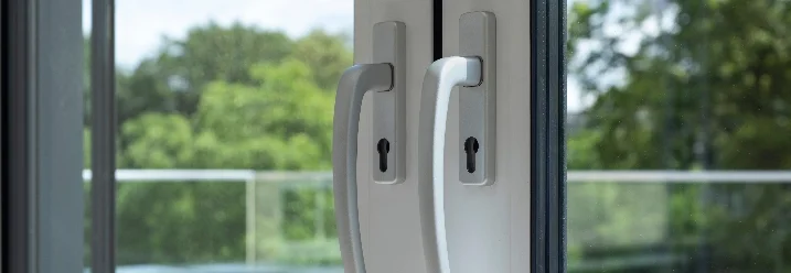 Zwei weiße Türgriffe an einer Balkontür.